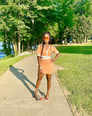 Lady poses wearing orange and white skirt set